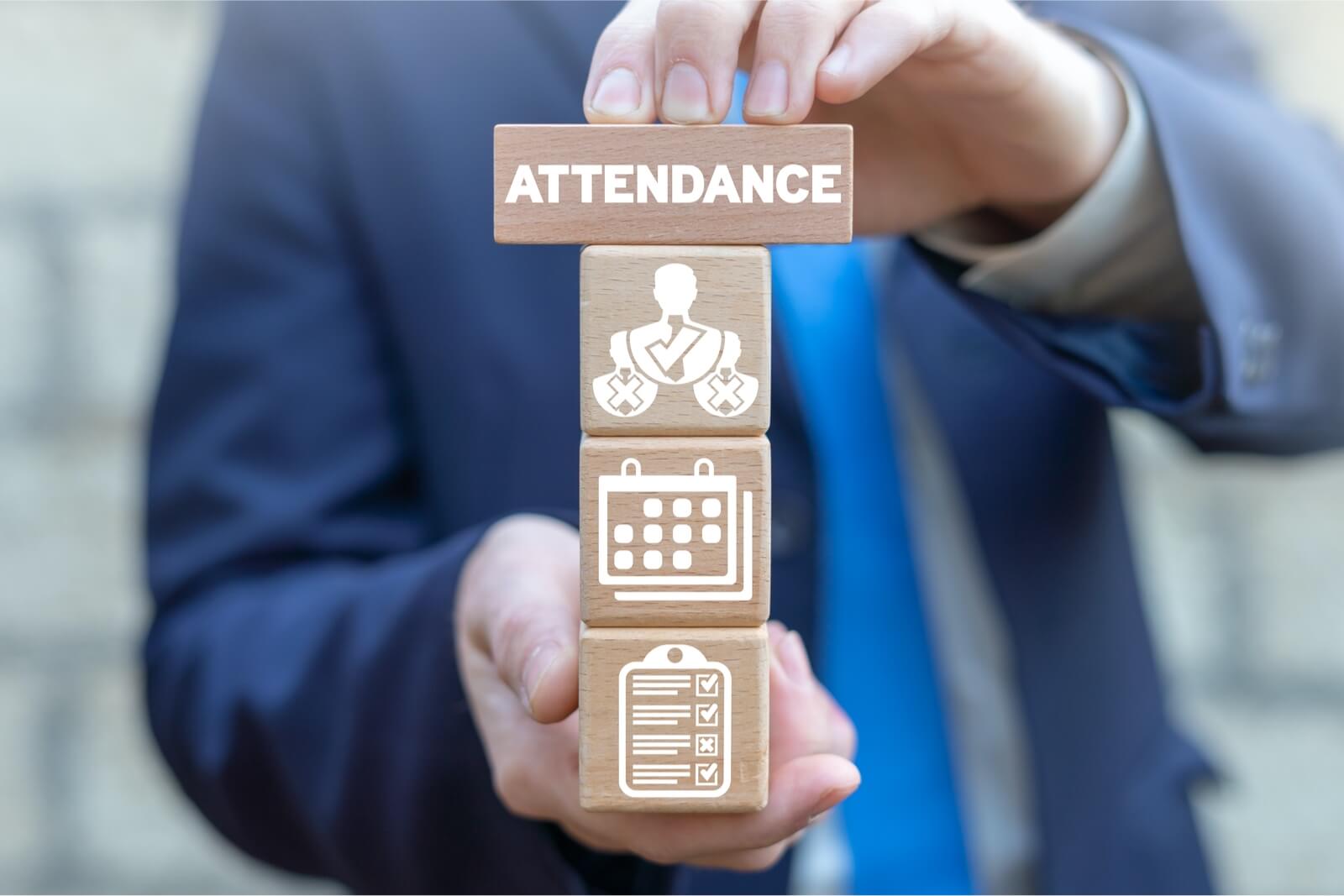 A person is holding wooden cubes that feature attendance tracking